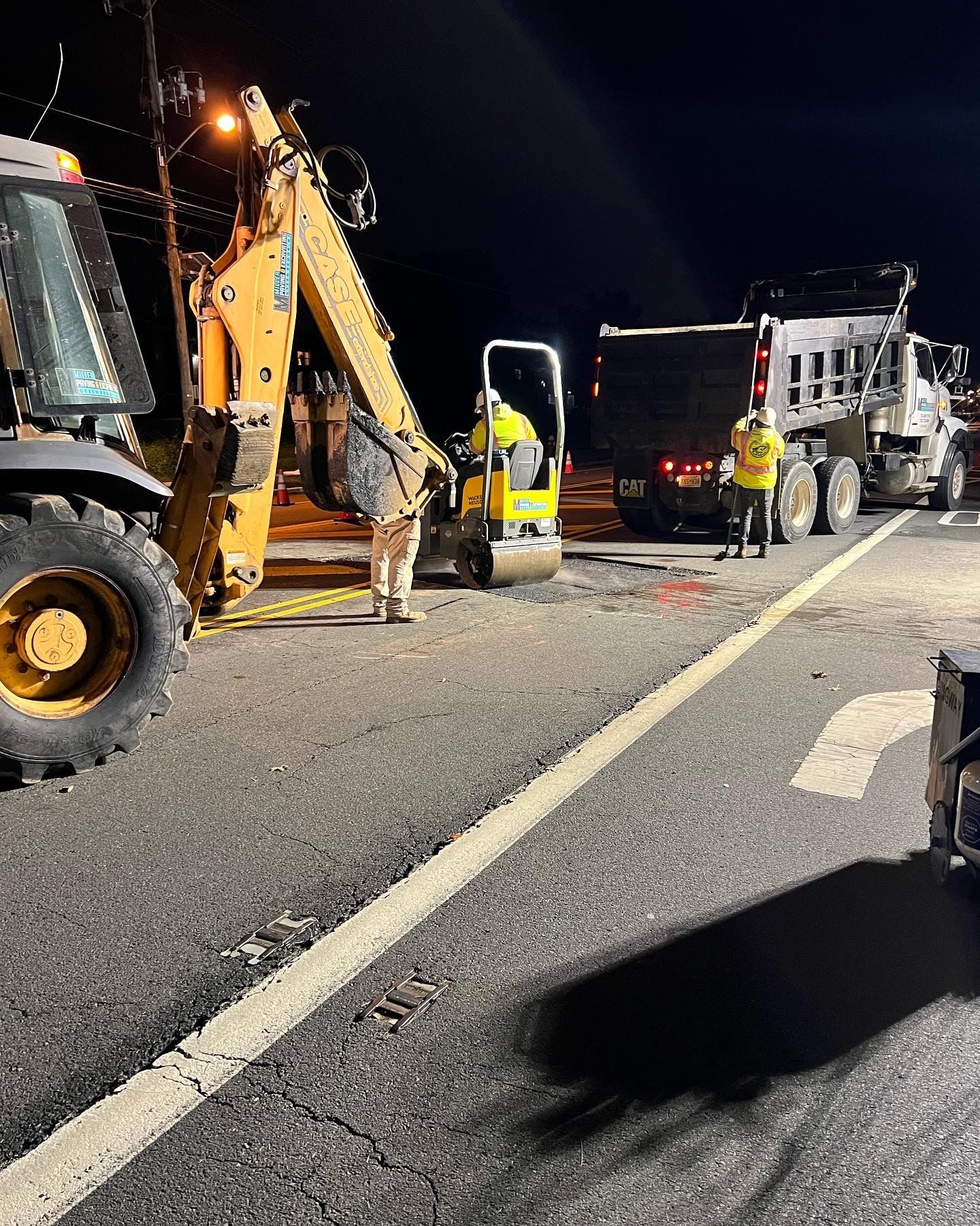 A group of construction workers are working on a road at night.