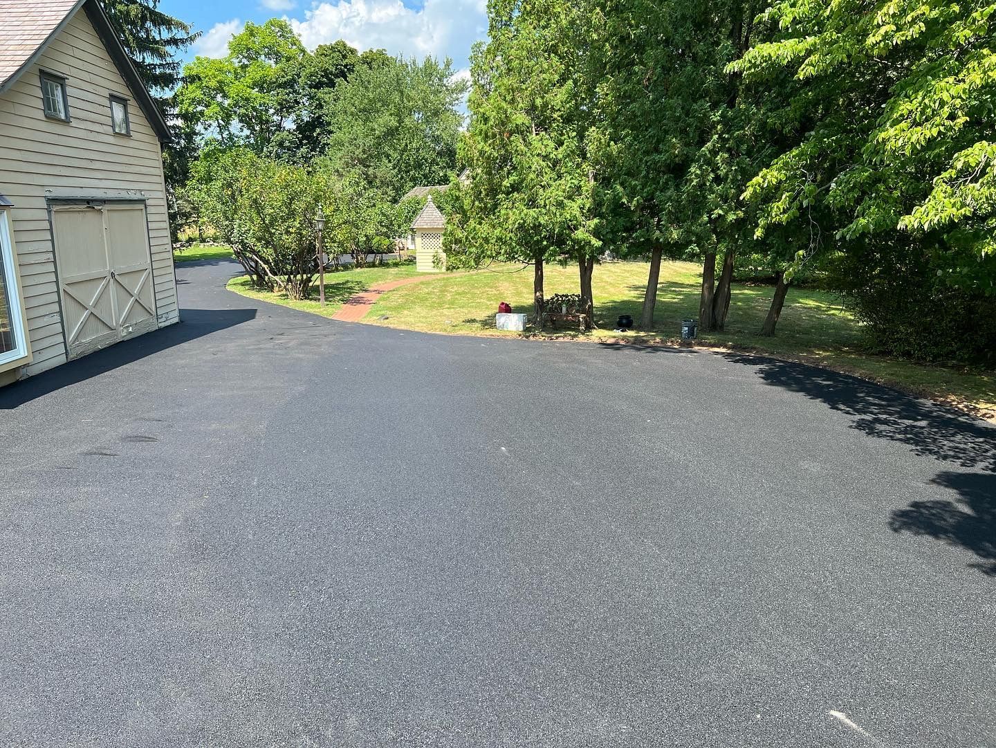 A driveway leading to a house with a garage and trees in the background.