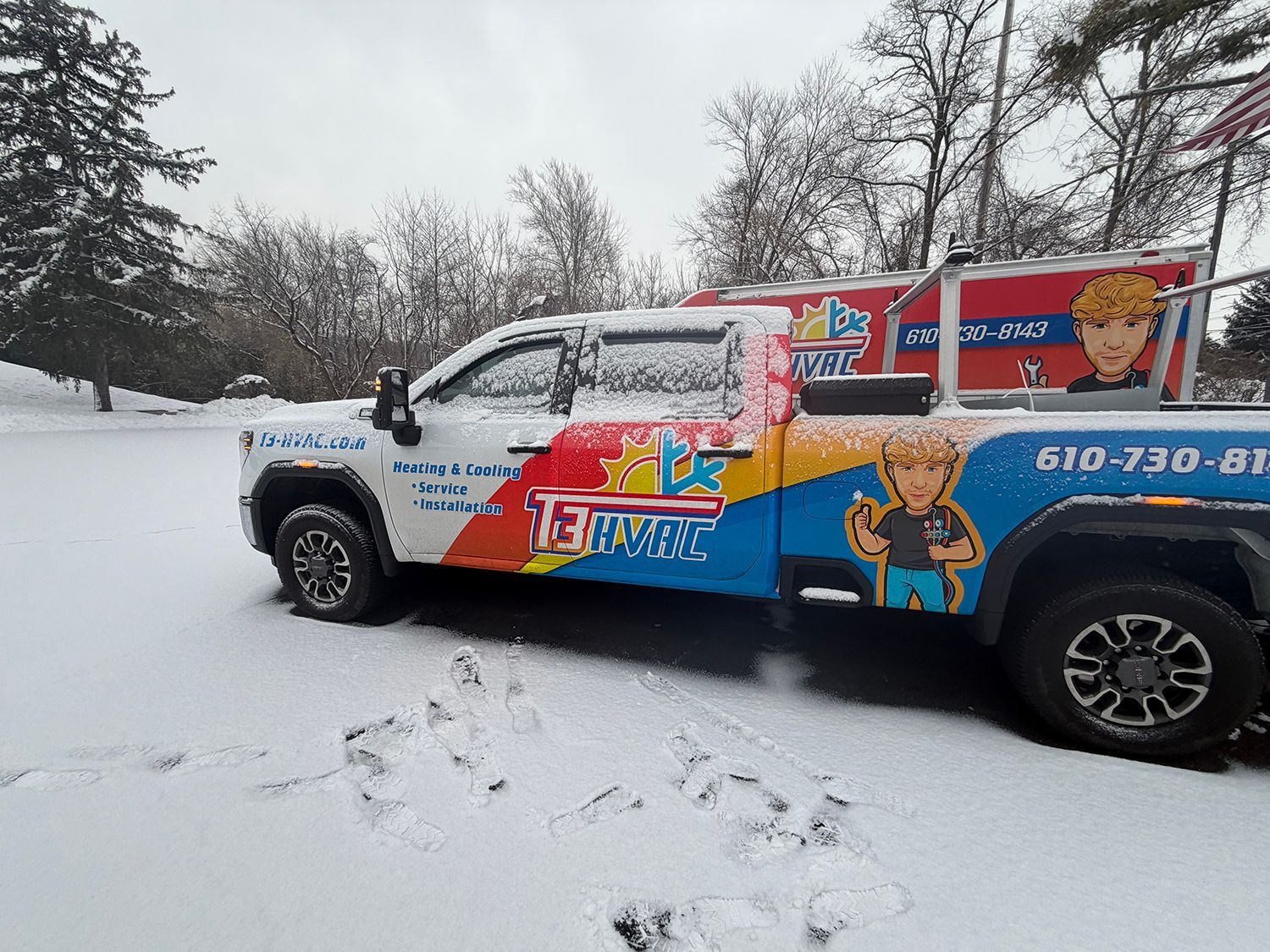 A truck with colorful vinyl branding parked in a snowy landscape.