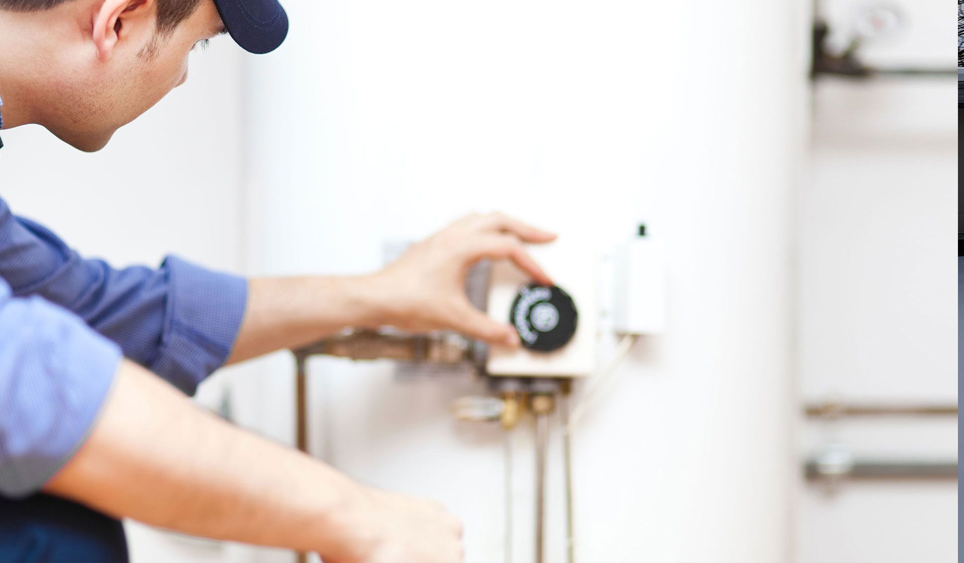 A technician adjusting the temperature dial on a water heater.