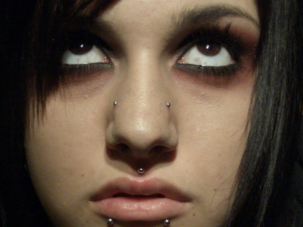 A close up of a woman 's face with multiple piercings