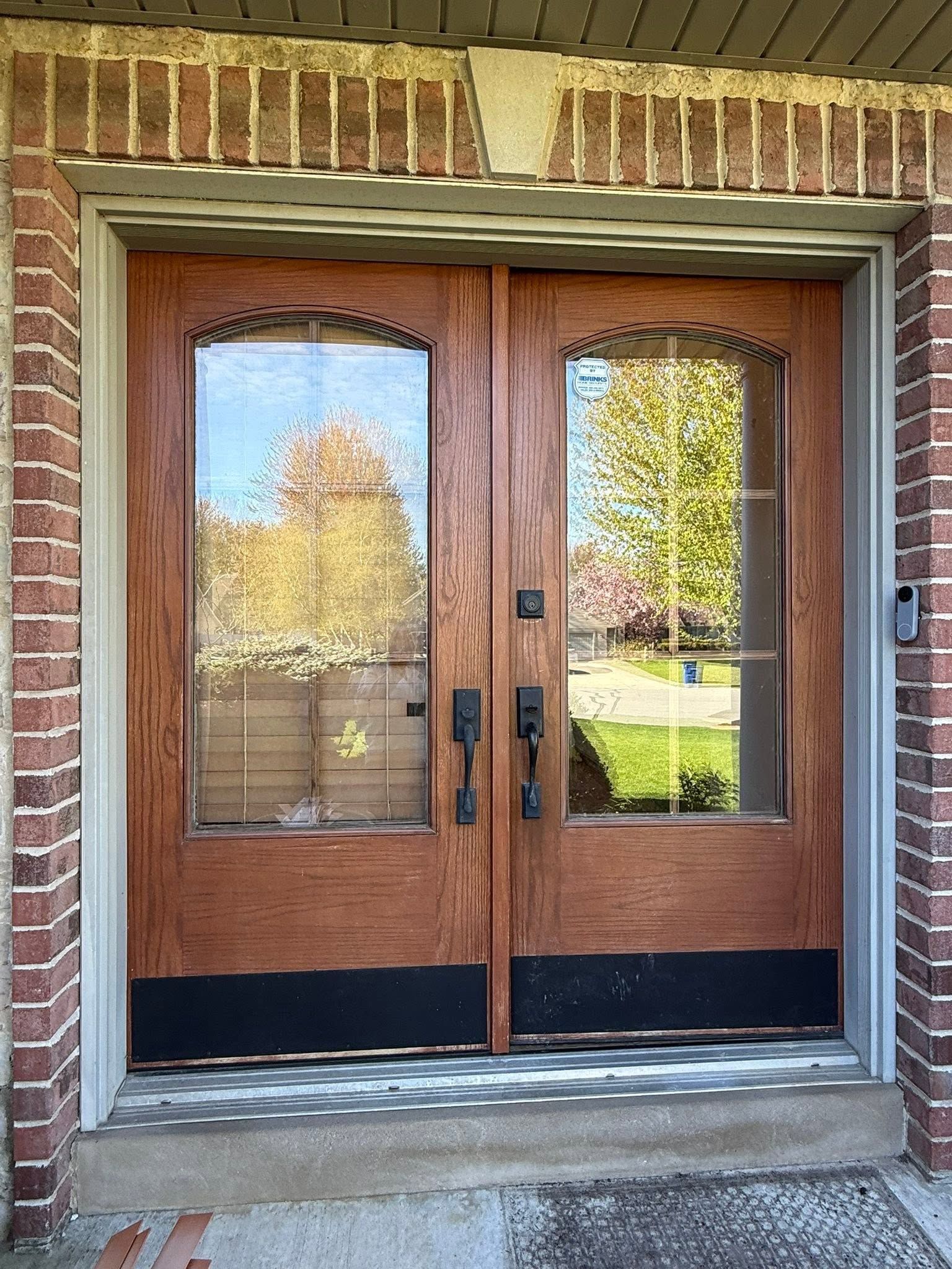 Wooden double front doors with glass panes set in a brick entryway