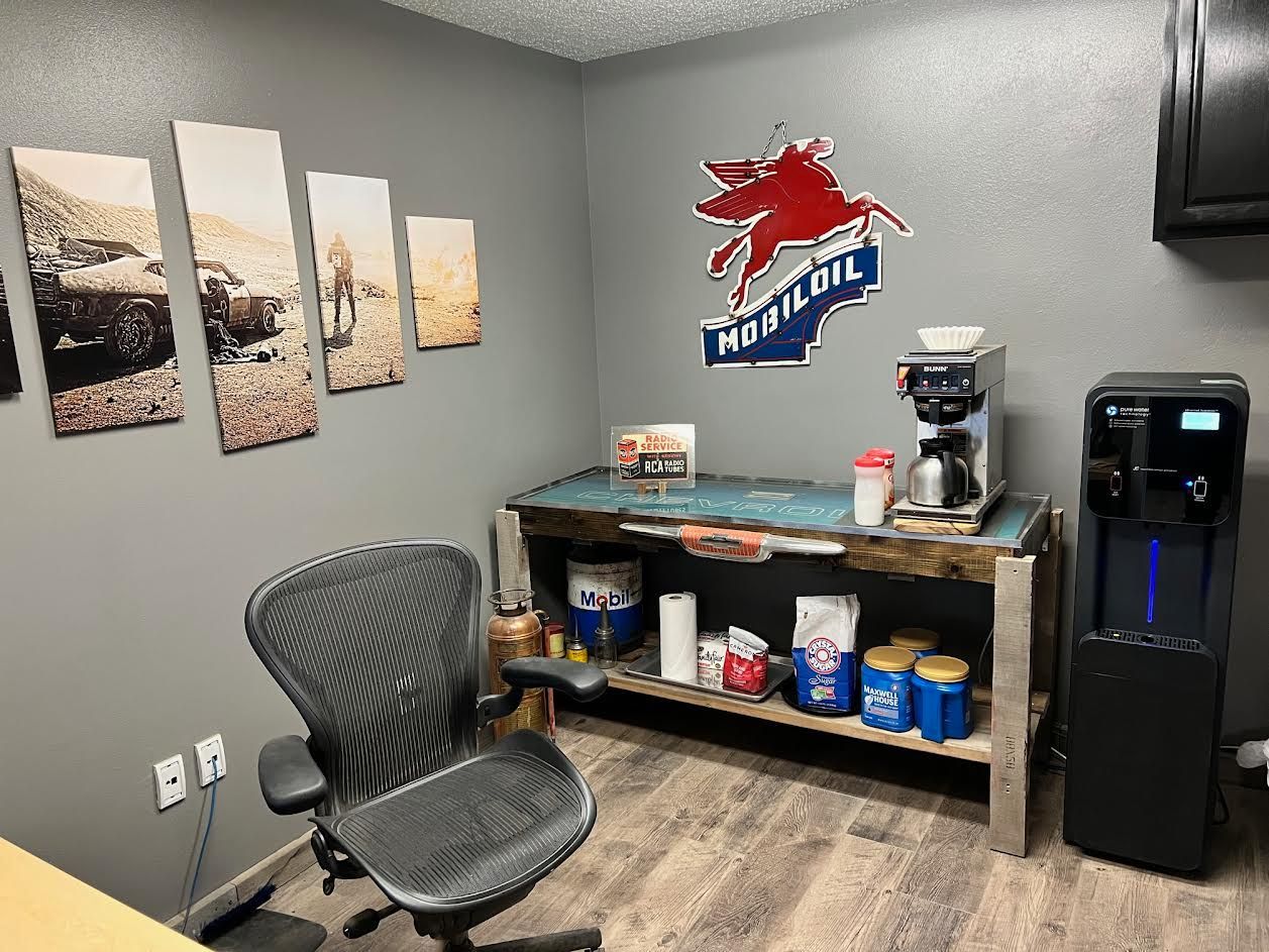 A room with a chair , table , and coffee maker.