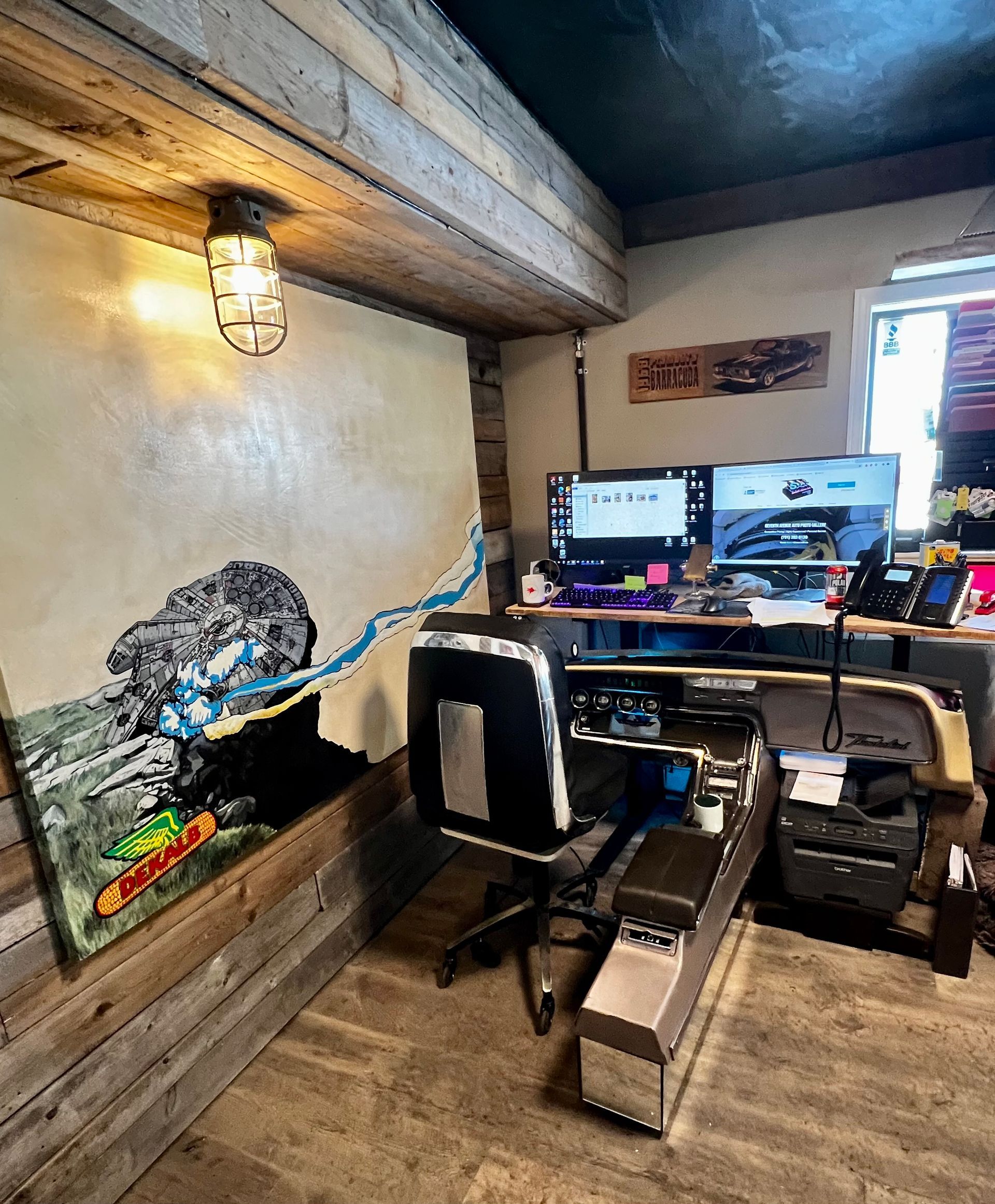 A room with a desk, chair, computer and a painting on the wall.