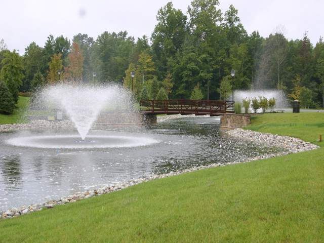 A pond with a fountain and a bridge in the background