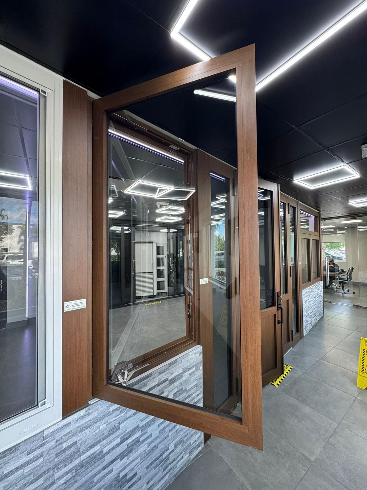 Wooden door with clear glass open, displaying the interior of a showroom.