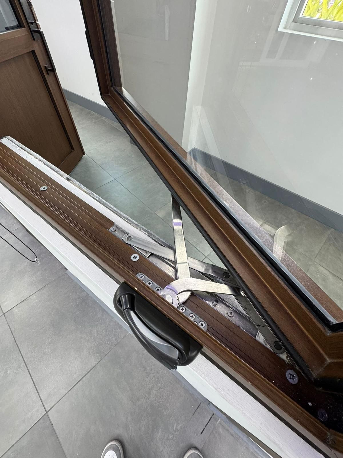 Opened brown window with a black handle, hinges, and white frame.