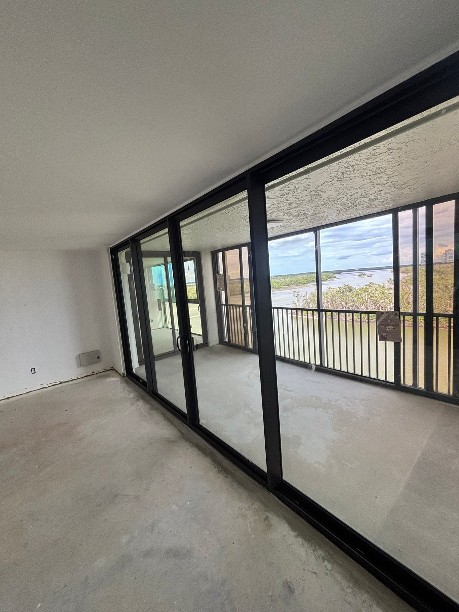 Interior view of a room with large sliding glass doors and a balcony overlooking a landscape.