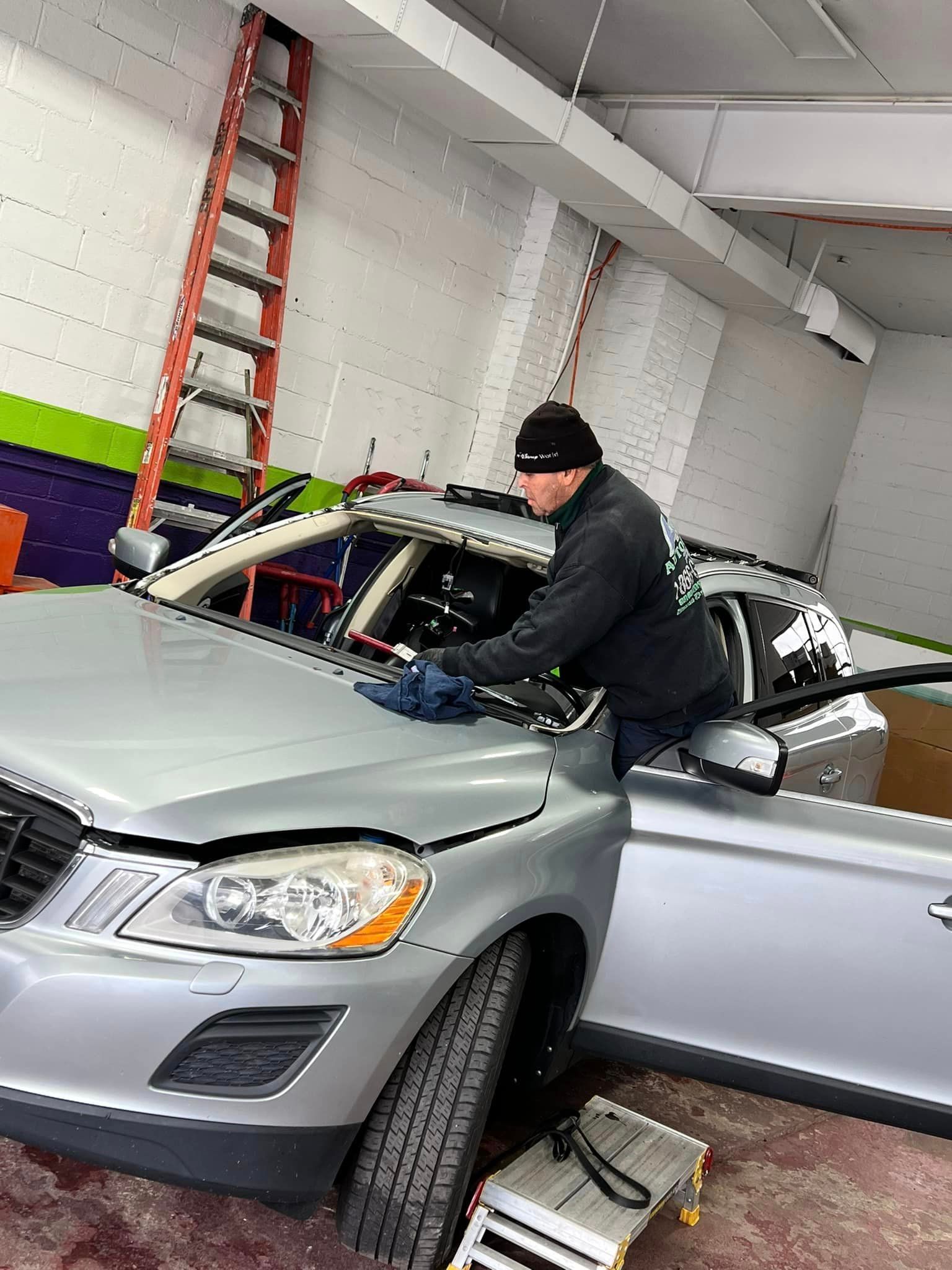 a man is cleaning the windshield of a car in a garage