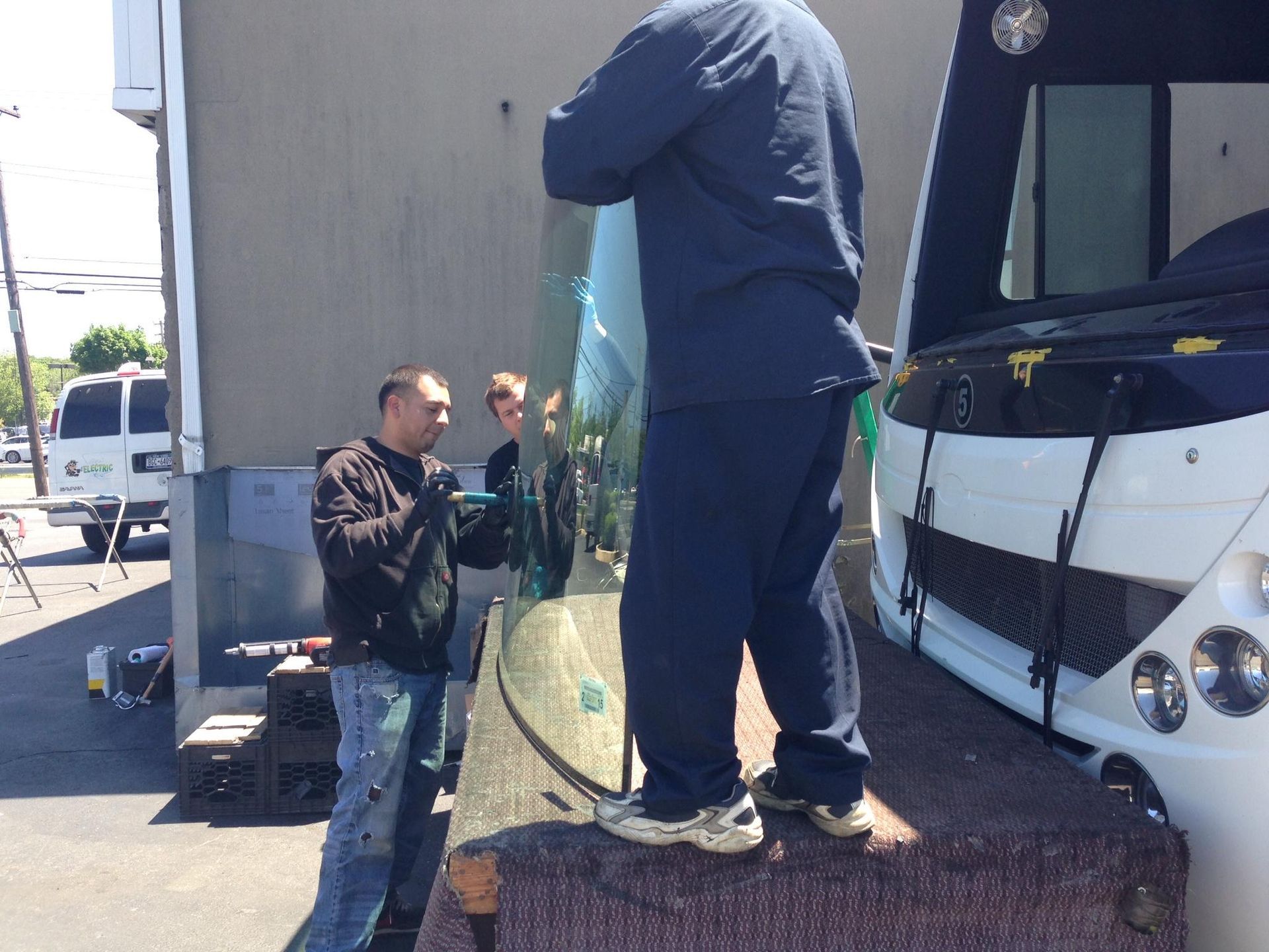two men are working on a windshield of a vehicle