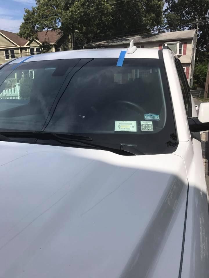 a white truck with a blue tape on the windshield is parked in front of a house
