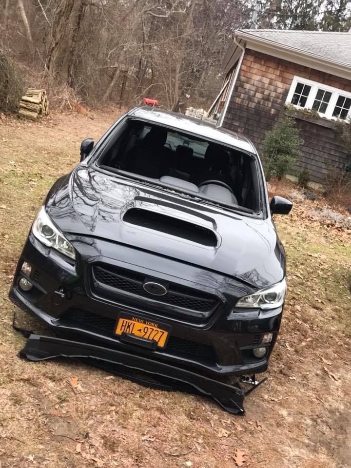 a black Subaru is sitting on the ground in front of a house