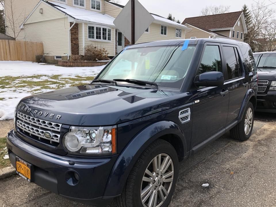 a blue land rover discovery is parked in front of a house