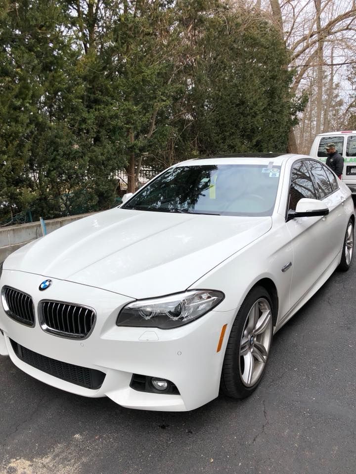 a white BMW 5 series is parked in a parking lot