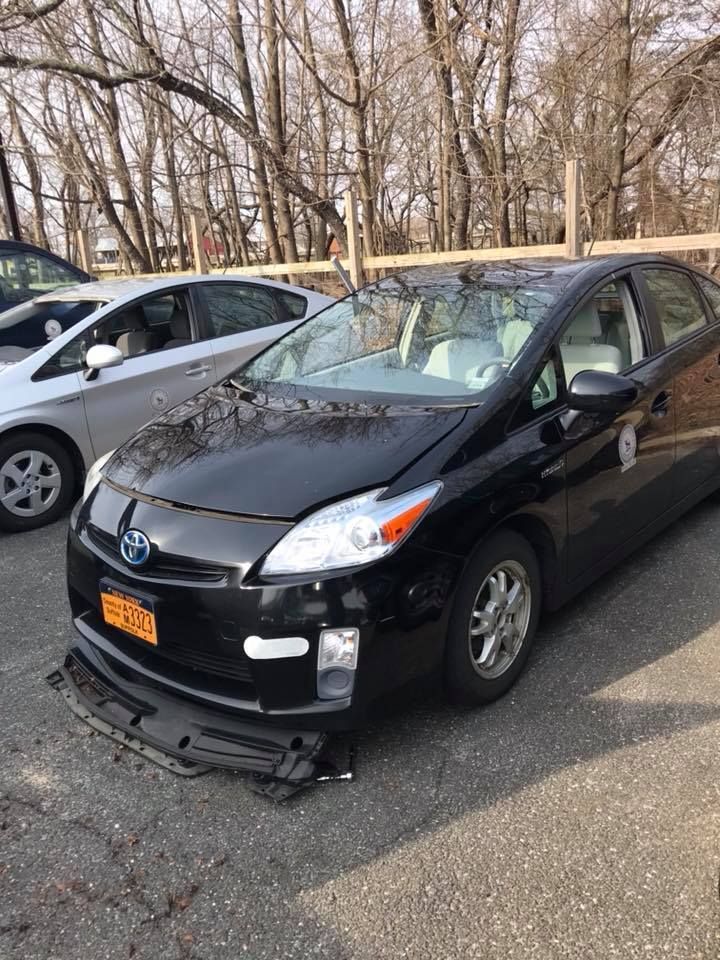 a black Toyota Prius is parked next to a white Prius in a parking lot