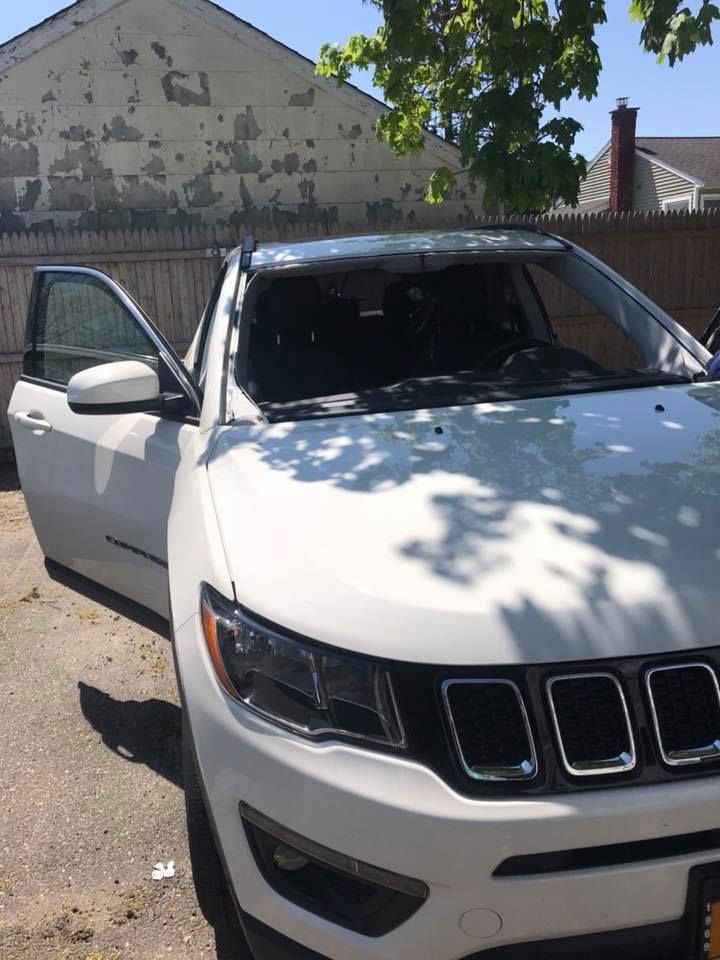 a white jeep compass is parked in front of a building