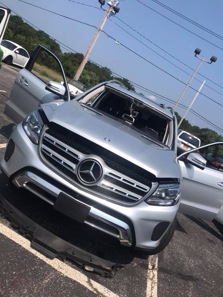 a silver Mercedes Benz SUV is parked in a parking lot with its doors open