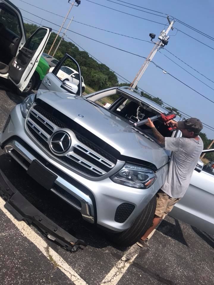 a man is fixing the windshield of a Mercedes Benz in a parking lot