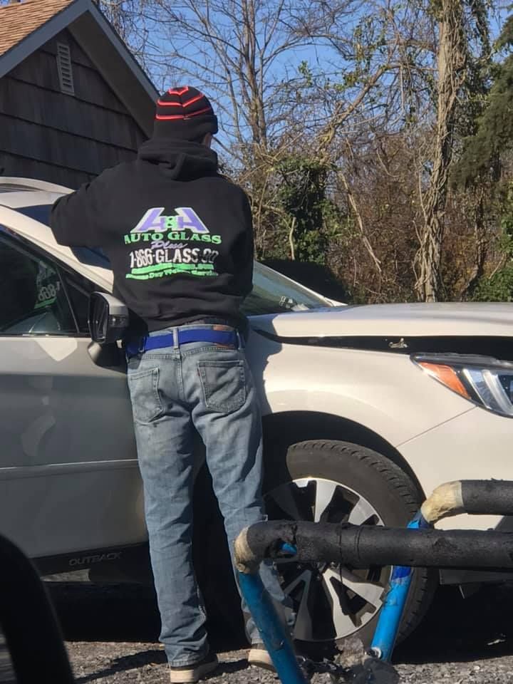a man in a black hoodie is standing next to a white car