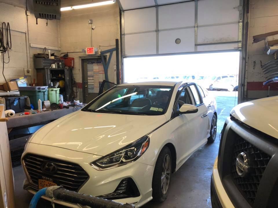 a white car is parked in a garage next to a nissan truck