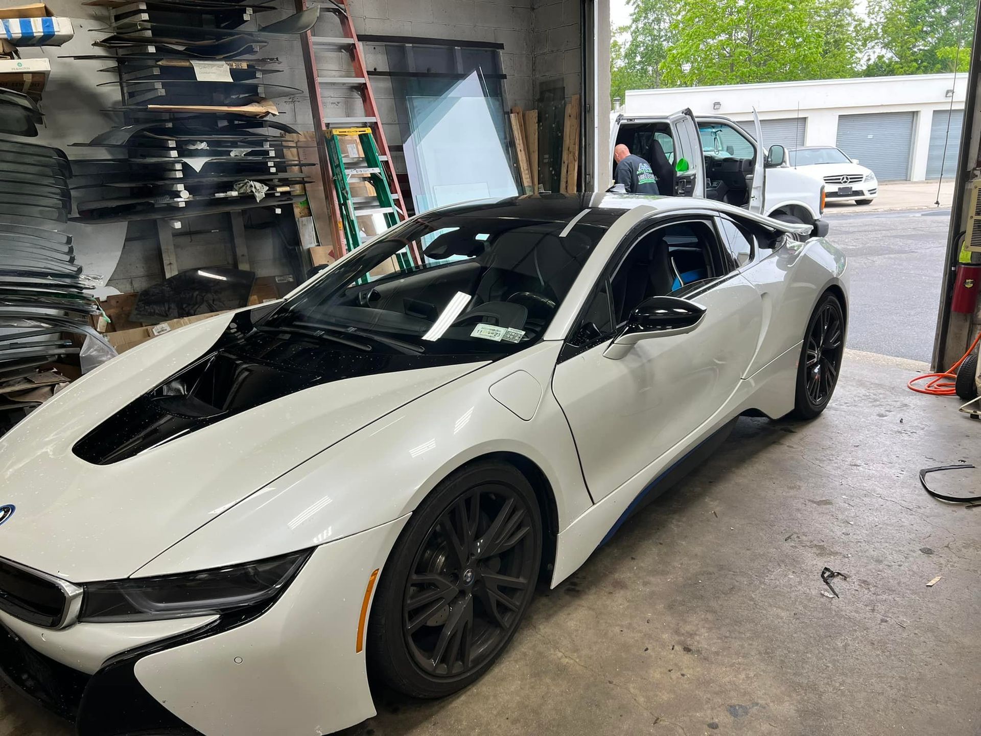 a white BMW i8 is parked in a garage with its hood open