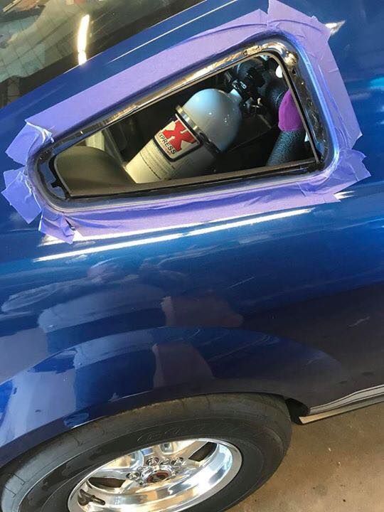 a blue car is sitting in a garage with purple tape on it