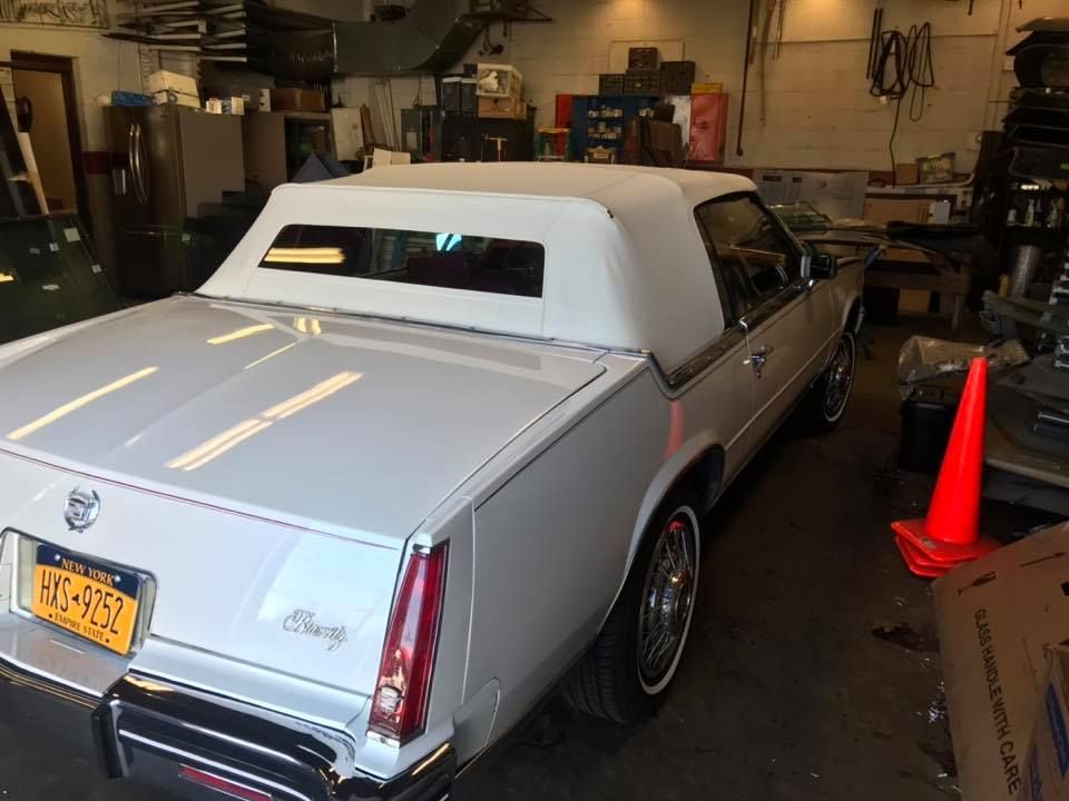 a white Cadillac is parked in a garage with a New York license plate