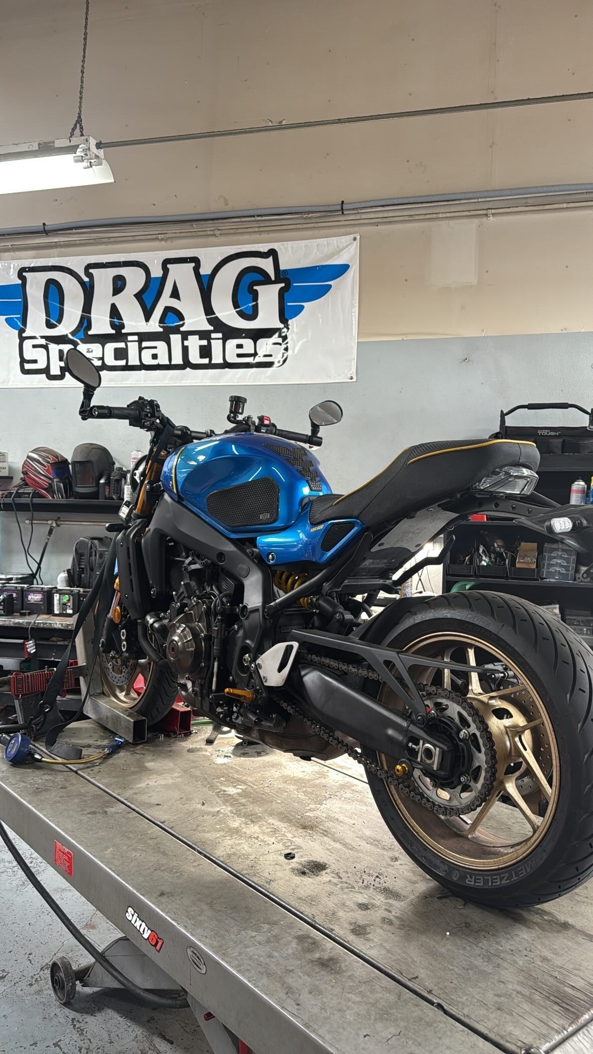 Blue and black motorcycle on a lift in a shop with a 