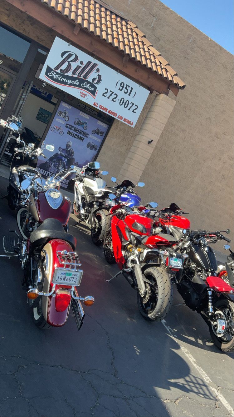 Motorcycles parked outside Bill's Motorcycle shop, with a red Indian motorcycle prominent.