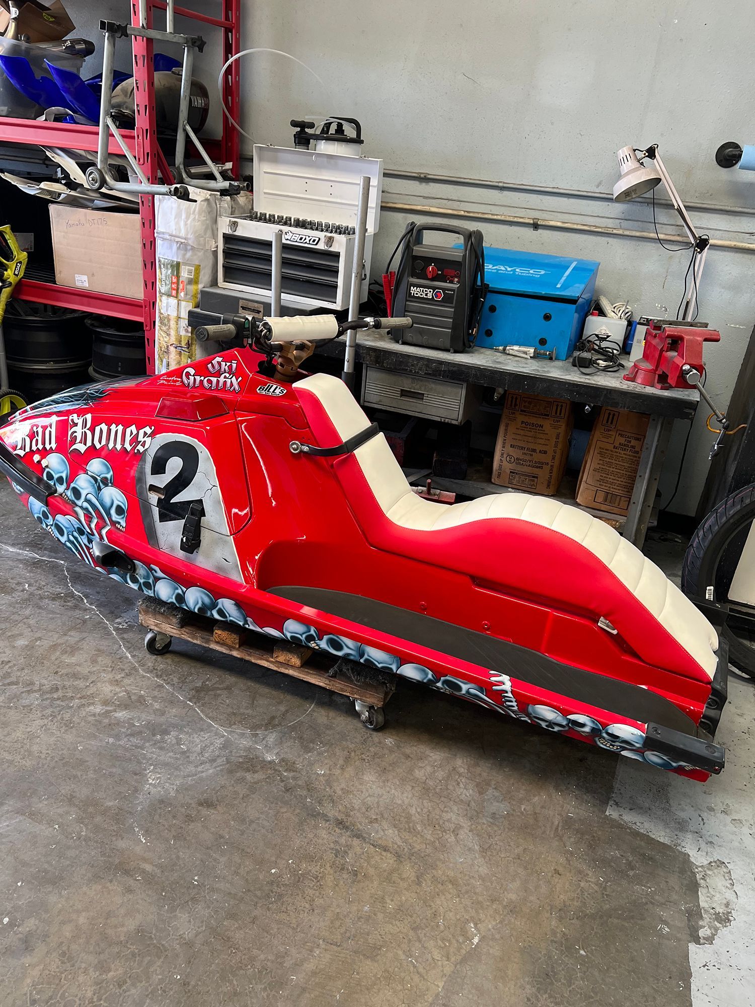 Red jet ski with skull graphics and the number 2, in a garage setting.