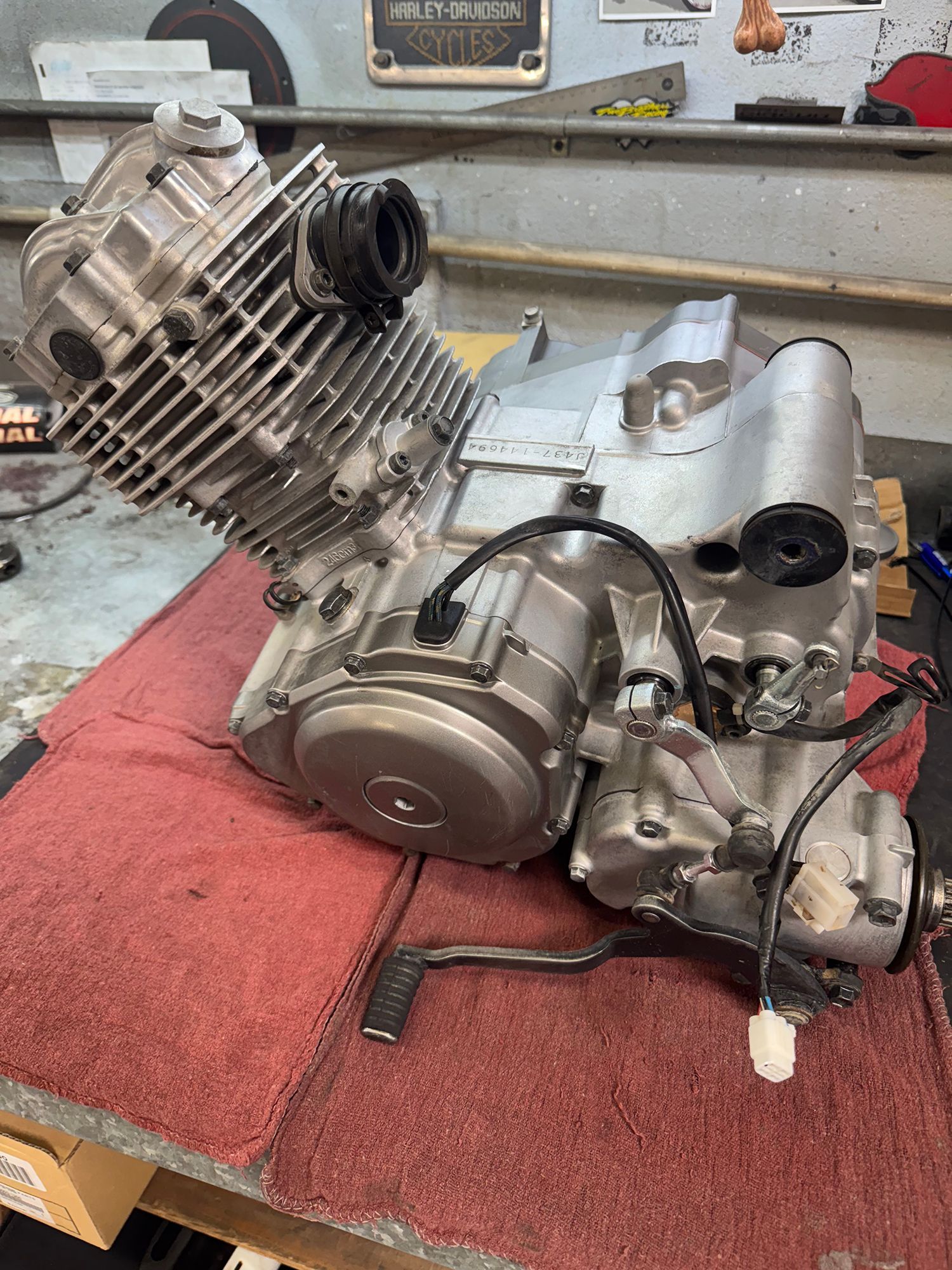 Motorcycle engine on a red cloth, with silver metal and black components visible.
