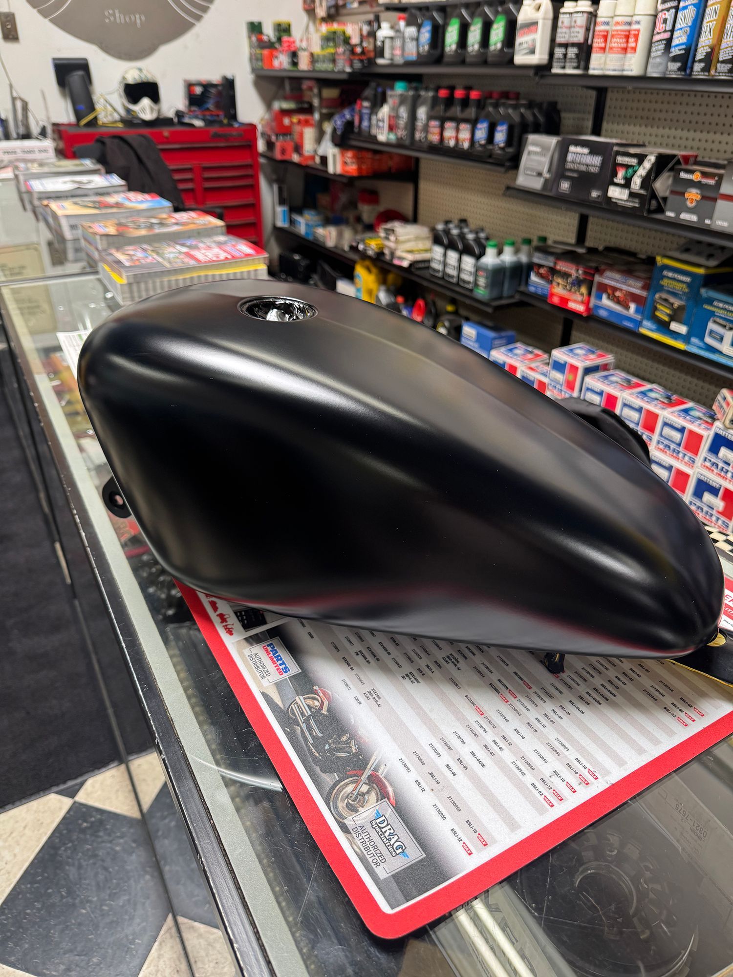 Black motorcycle gas tank on a counter, in a store.