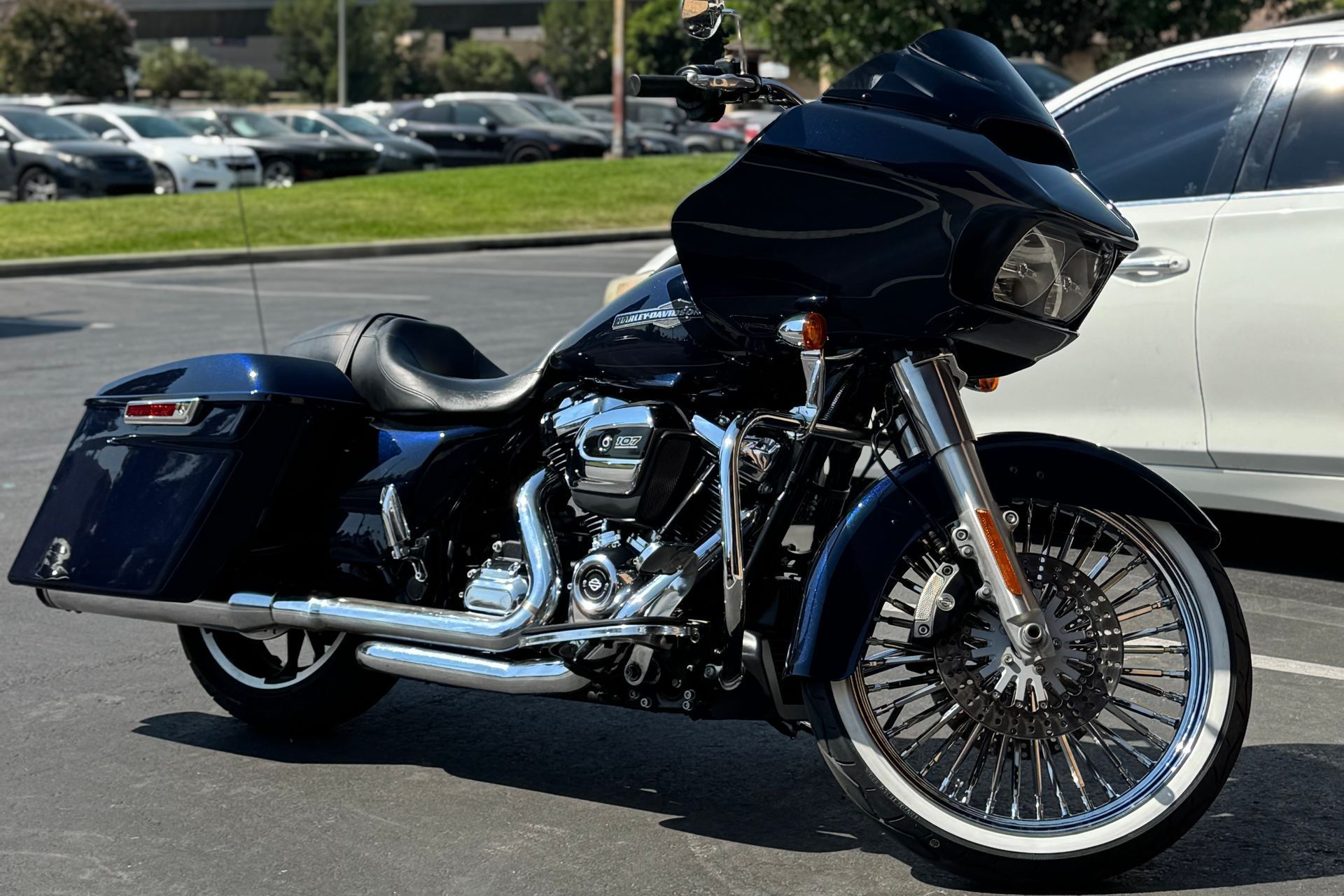 Dark blue Harley-Davidson motorcycle parked in a lot, chrome details, white wall tires.