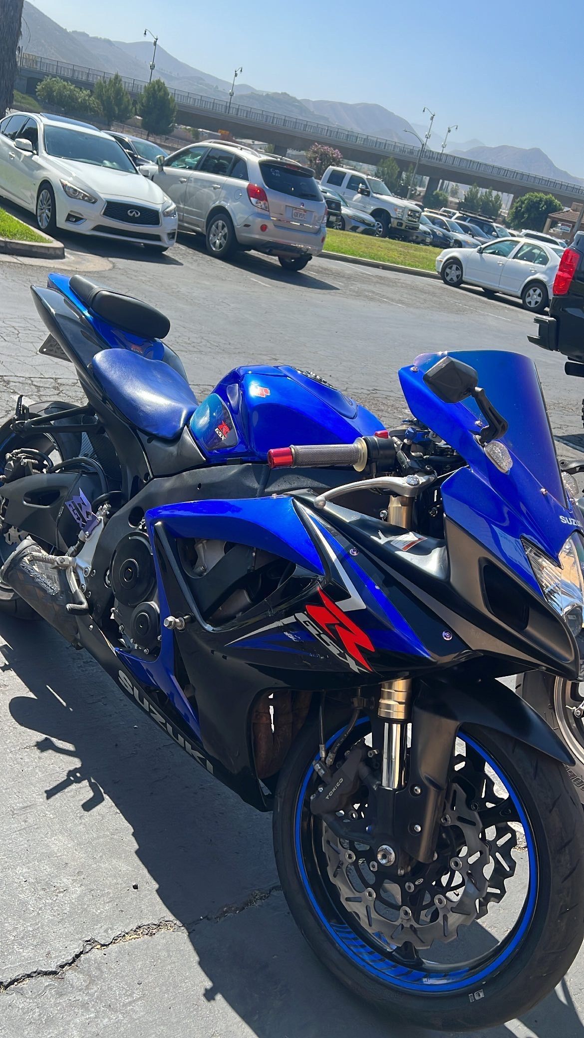 Blue and black Suzuki motorcycle parked outdoors on a sunny day.