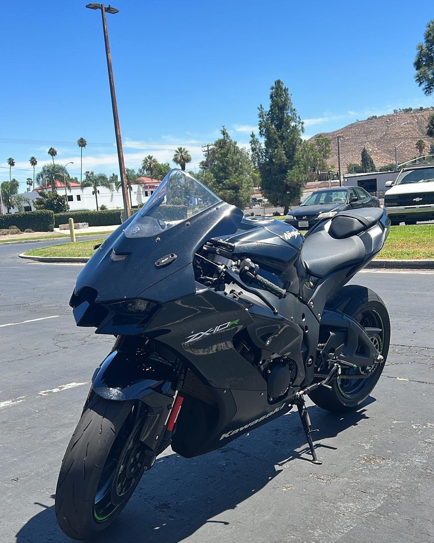 Black sport motorcycle parked outdoors on a sunny day.