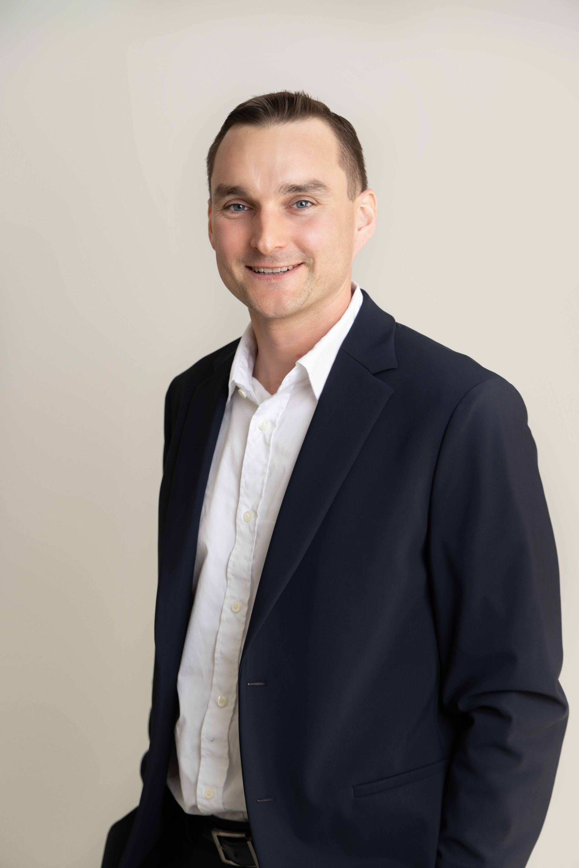 A man in a suit and white shirt is standing with his hands in his pockets.