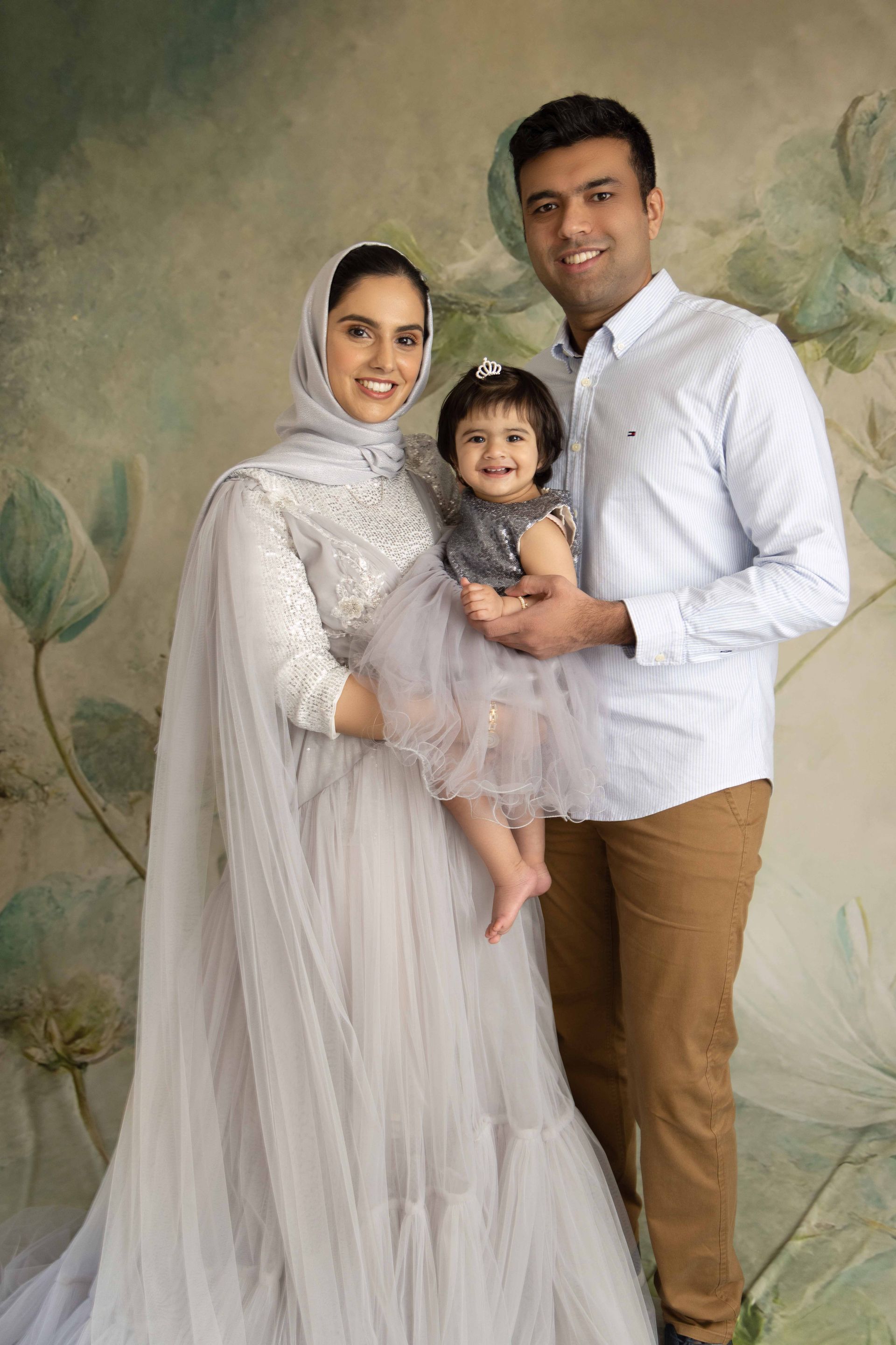 A man and woman are holding a baby in a red room.