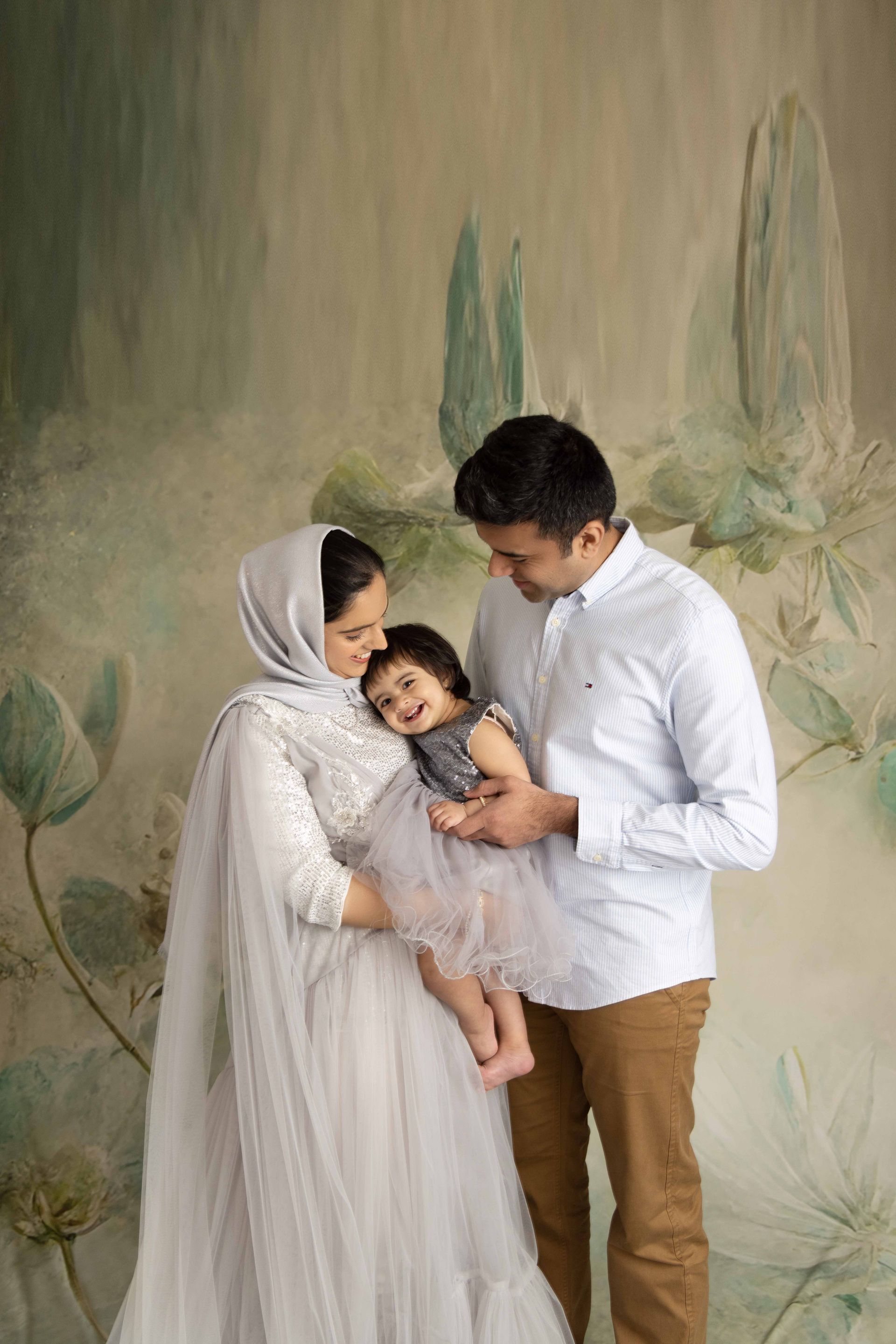 A man and woman are standing next to each other holding a baby.