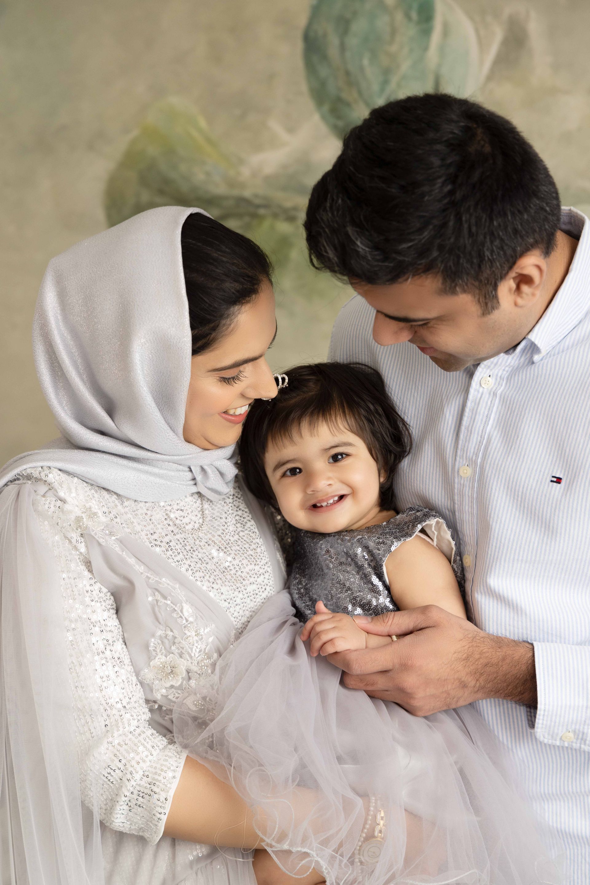 A family is walking down a sidewalk holding hands.