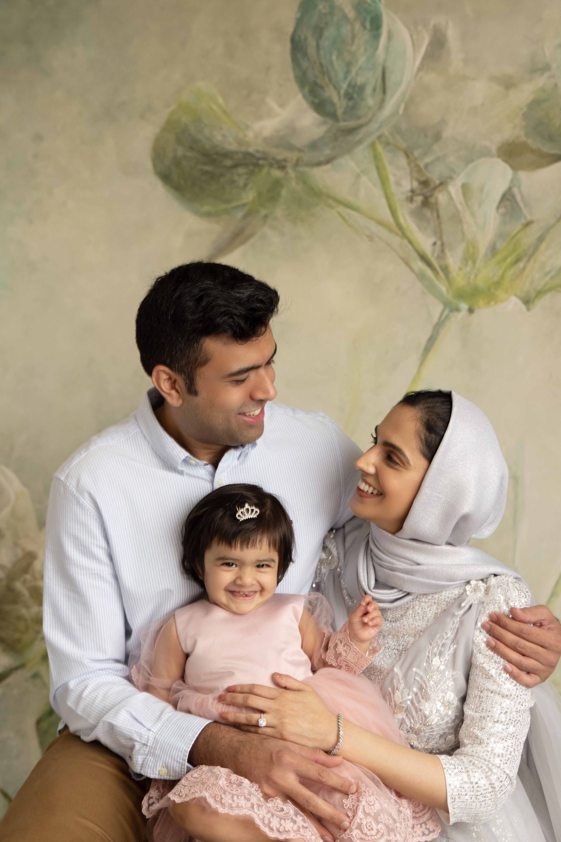 A man and woman are sitting next to each other holding a little girl.