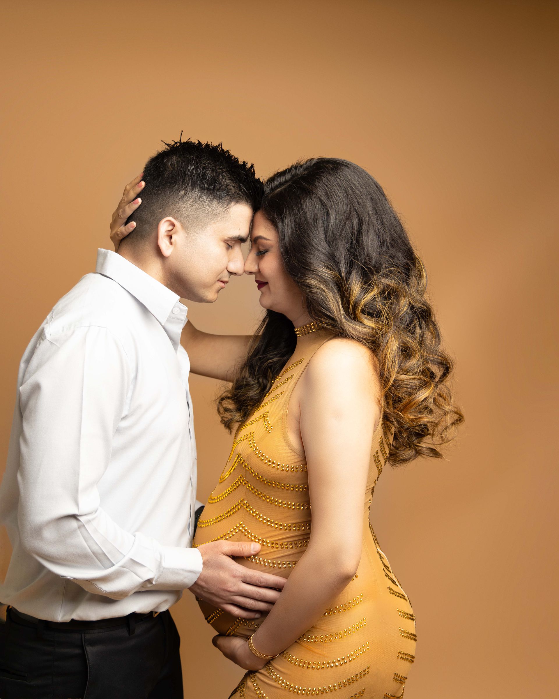A pregnant woman in a yellow dress is standing next to a man in a white shirt.