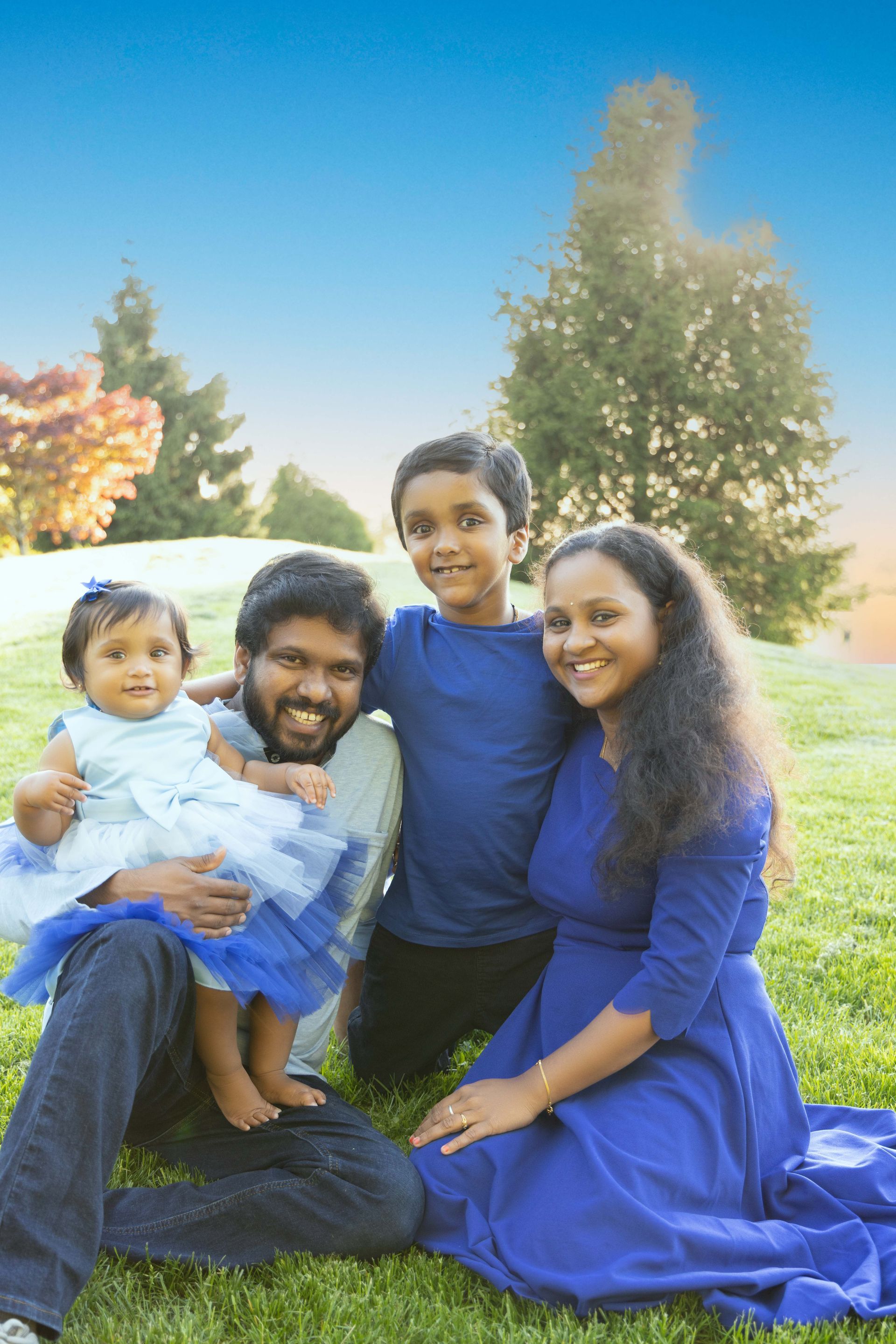 A family is laying on a picnic blanket in the grass.