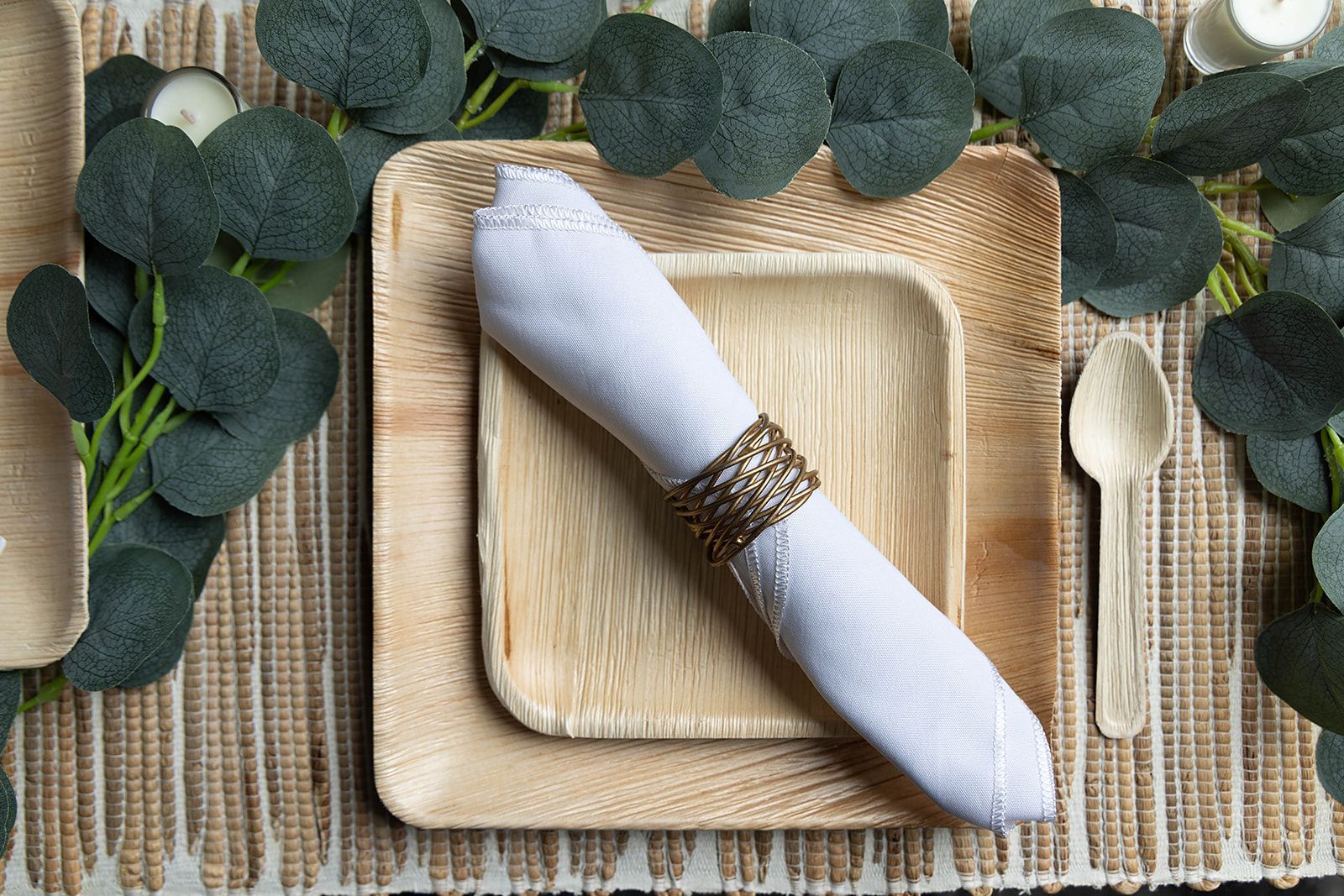 A table setting with wooden plates , spoons , and a napkin.