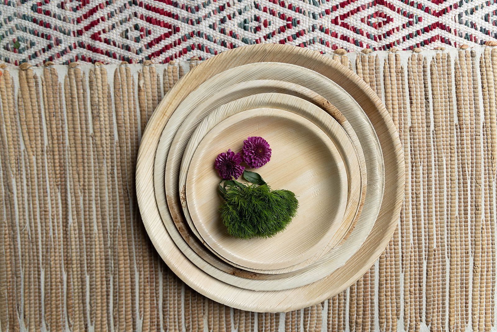A stack of wooden plates with flowers on them on a table.