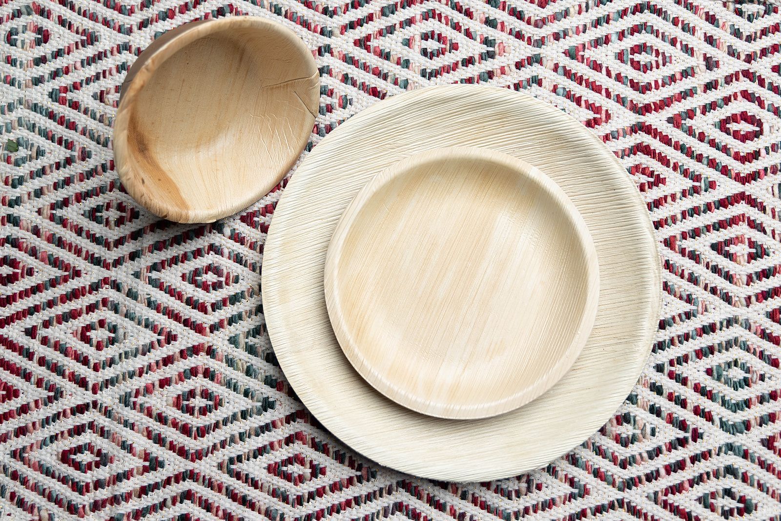A wooden bowl and plates are sitting on a table.
