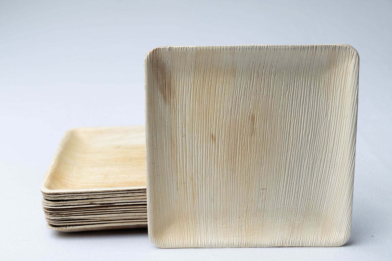 A stack of square wooden plates on a white surface.