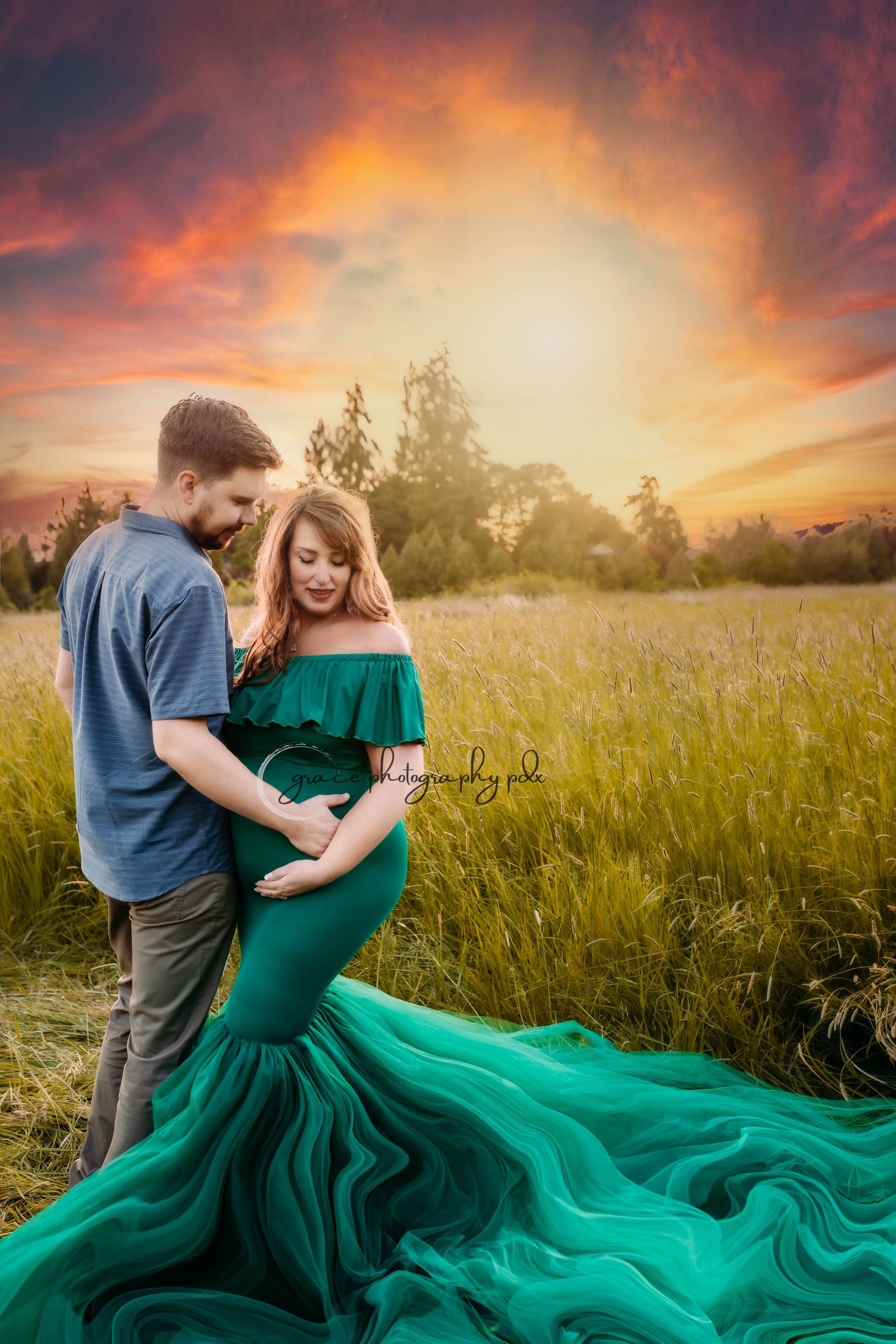 A pregnant woman in a green dress is standing next to a man in a field.