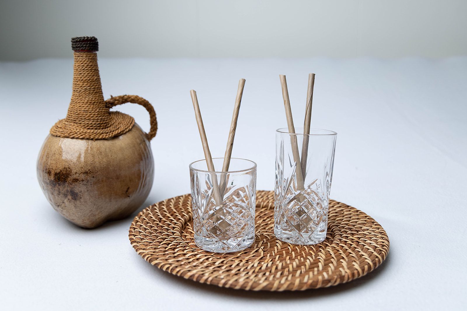 A wicker tray with two glasses and straws on it