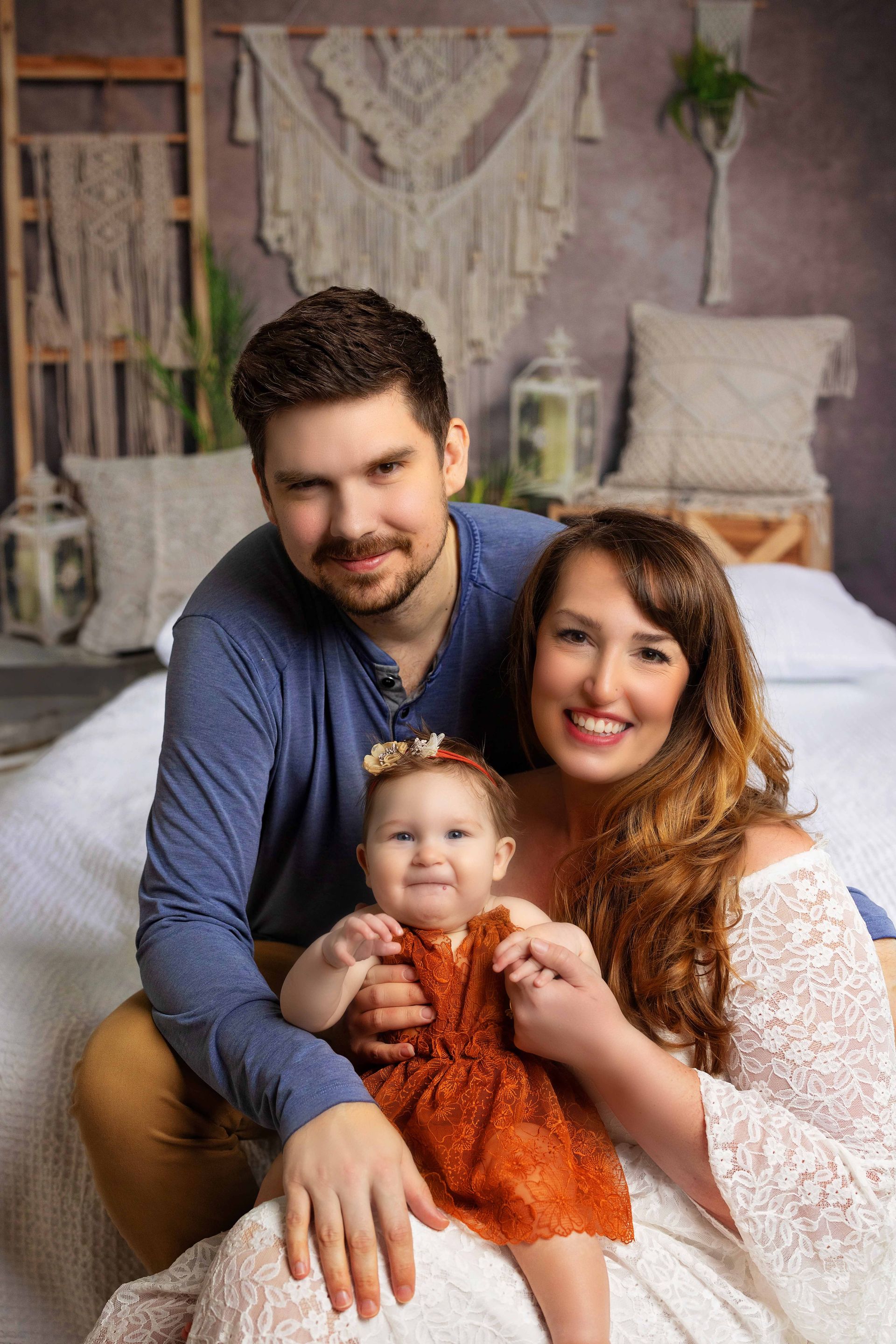 A family is posing for a picture while sitting on a bed.