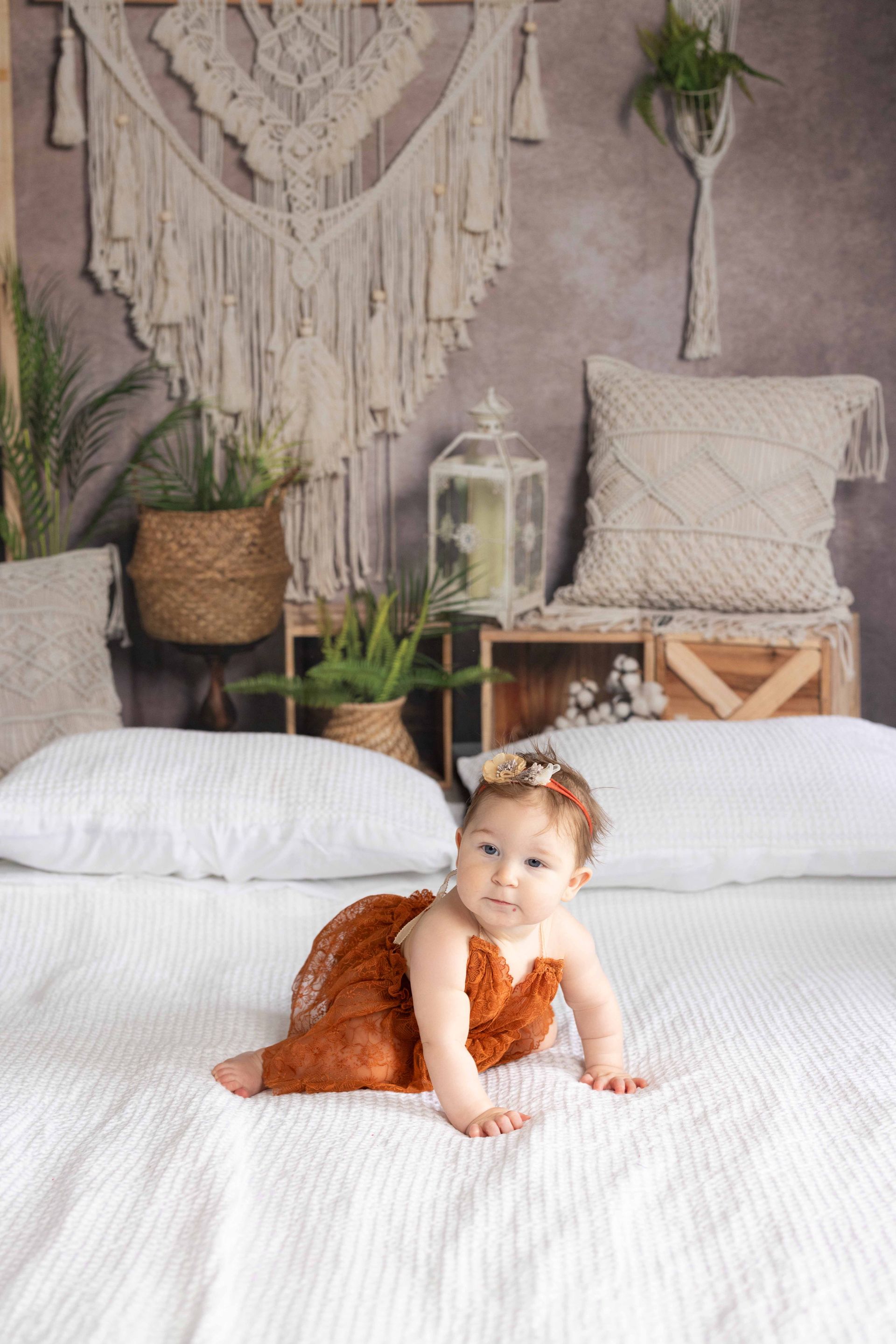 A baby is crawling on a bed in a room.